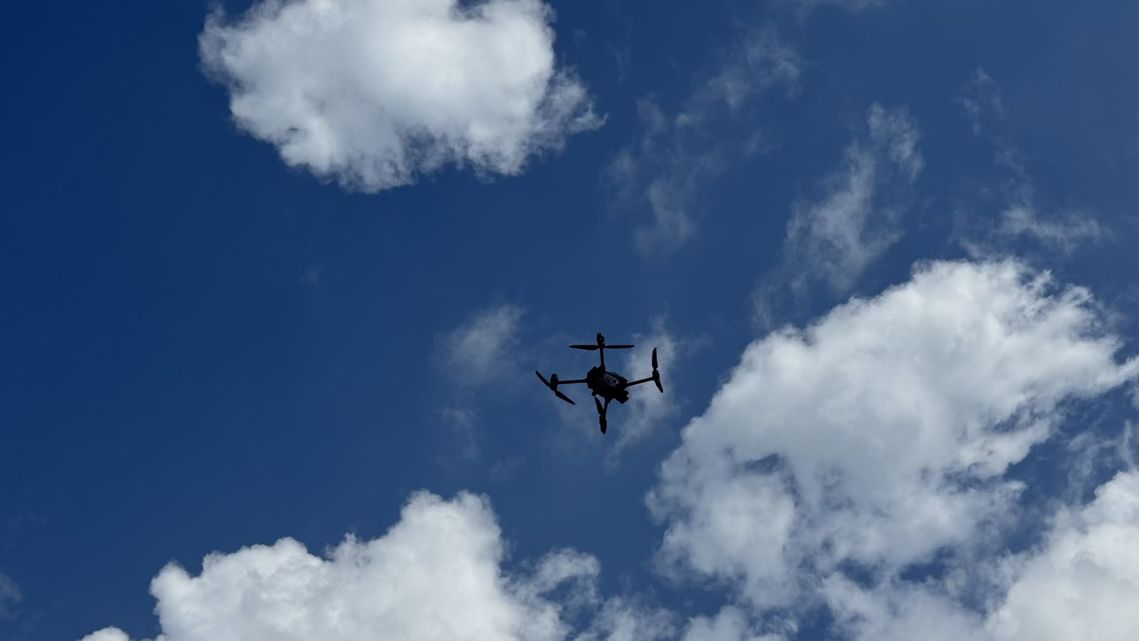 Quadcopter als Silhouette vor blauem Himmel mit Wolken