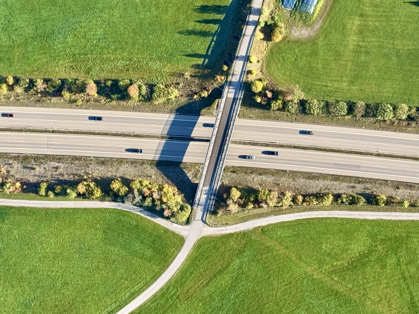 Luftbild einer Autobahnbrücke mit langem Schatten auf einer mehrspurigen Straße