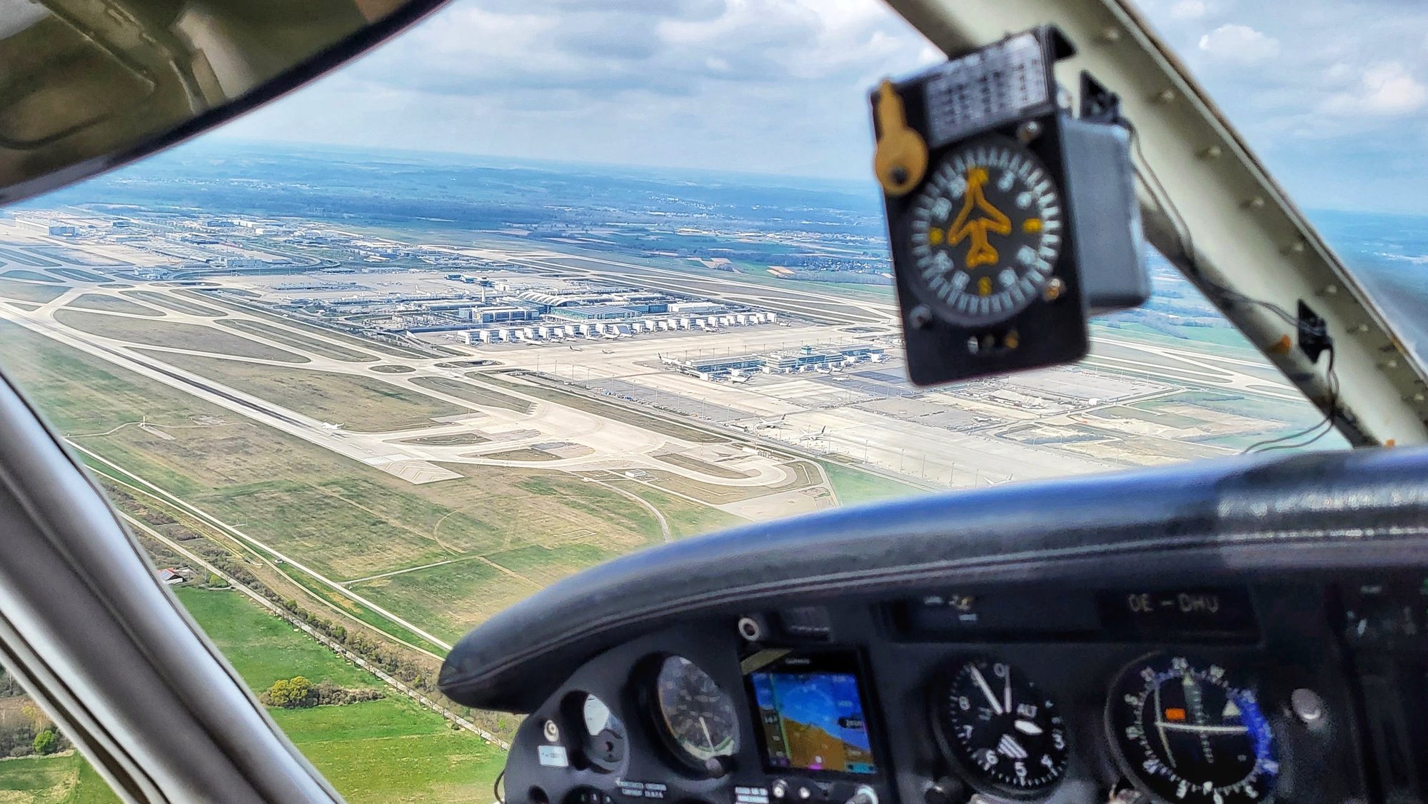 Blick aus dem Cockpit auf Instrumententafel und Flughafen mit Start- und Landebahnen