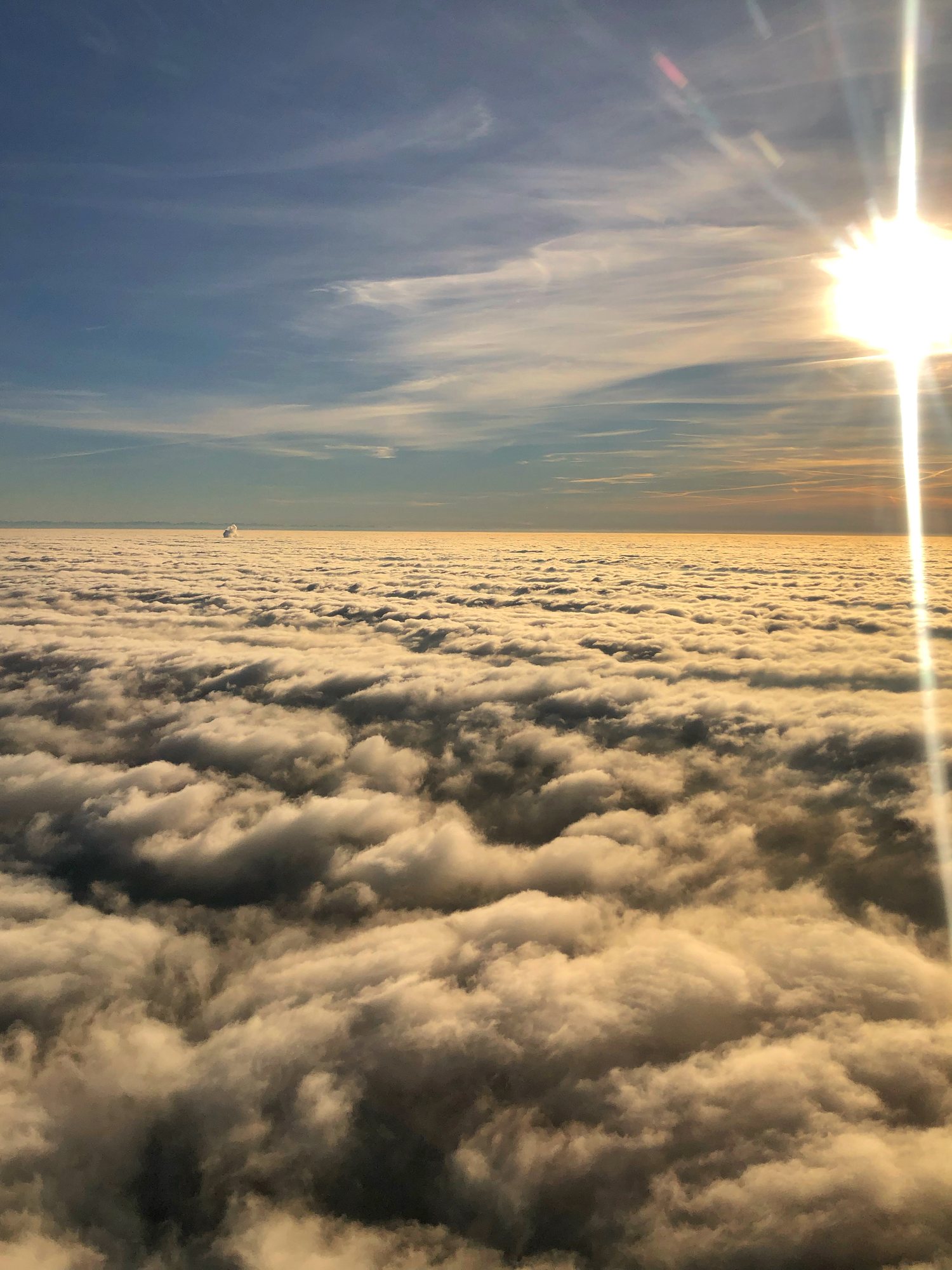 Blick aus dem Cockpit über eine geschlossene Wolkendecke im goldenen Licht